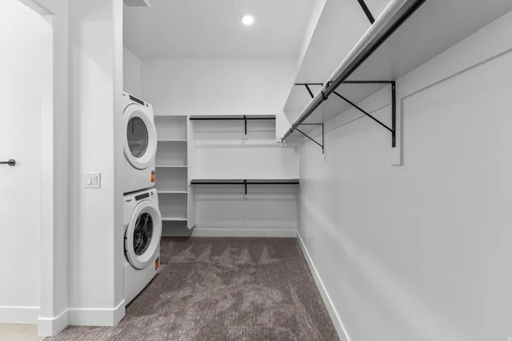 Integrated laundry area with stacked white appliances