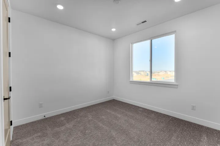 Recessed lighting, wall-to-wall carpeting, single window, white trim, and a paneled door with matte black hardware