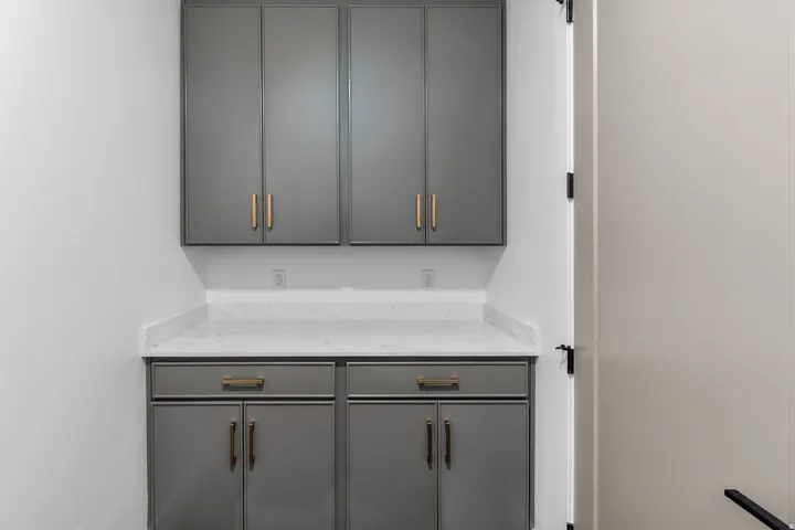 Built-in gray cabinetry with gold-tone hardware, white countertop, and white walls