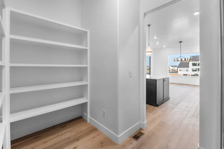 Built-in shelving, wood-finish flooring, recessed lighting, and a kitchen island with pendant lighting