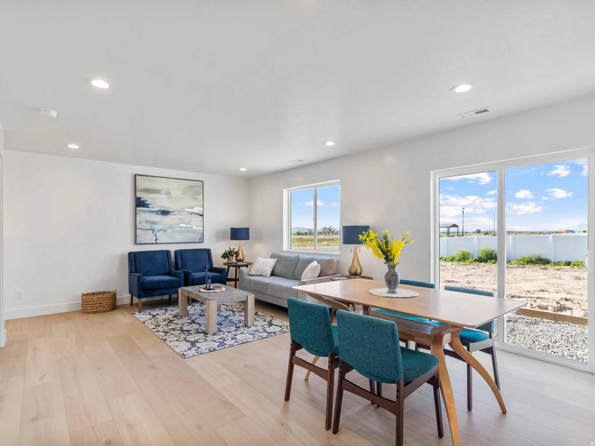Recessed ceiling lighting, light wood-finish flooring, white walls, and a sliding glass door to the exterior