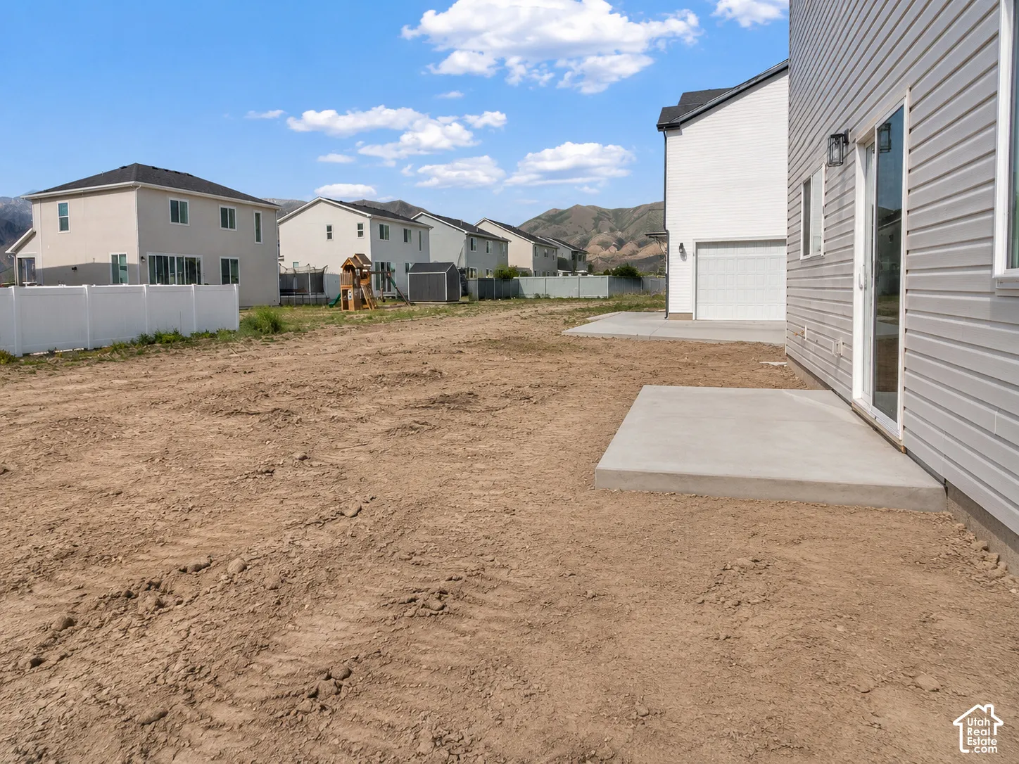 Rear yard with a concrete patio pad and a sliding glass door. AI was used to update the photo with the completed concrete.