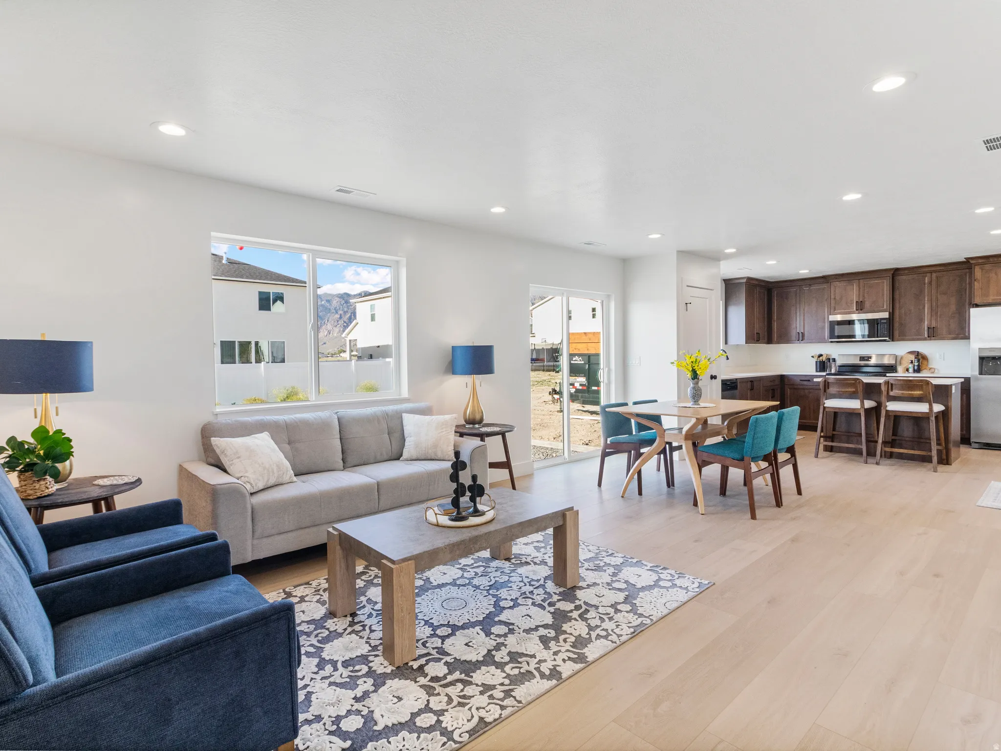 Open-concept living area with light wood-finish flooring, recessed lighting, and a large window