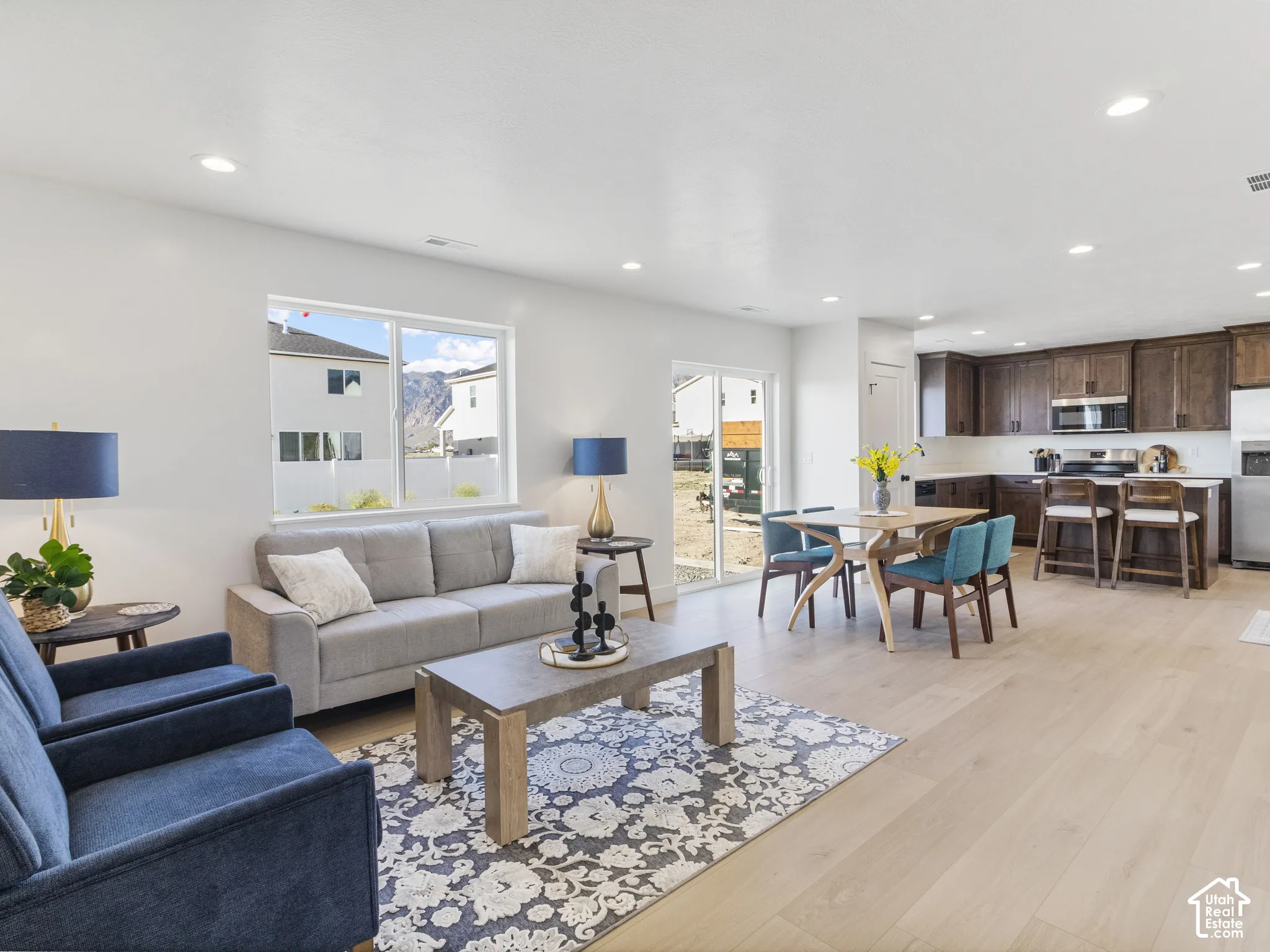 Open-concept living area with light wood-finish flooring, recessed lighting, and a large window