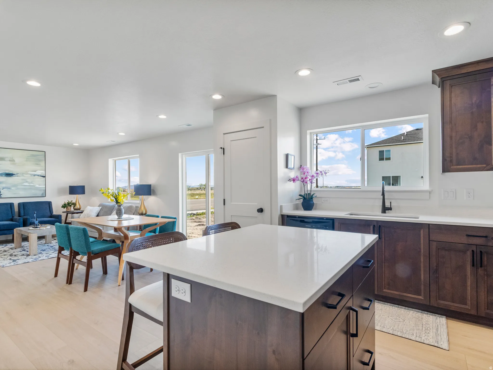 Kitchen island with white countertop, dark wood-finish cabinetry, and recessed lighting