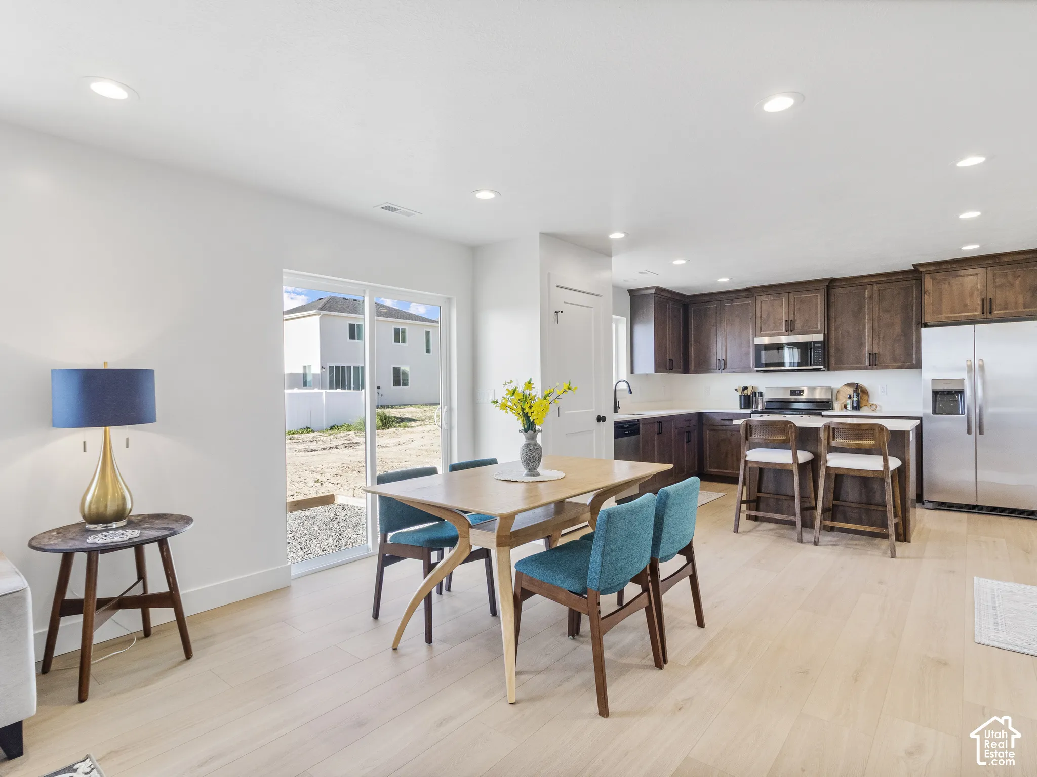 Open-concept living space with light wood-finish flooring, recessed lighting, and a sliding glass door
