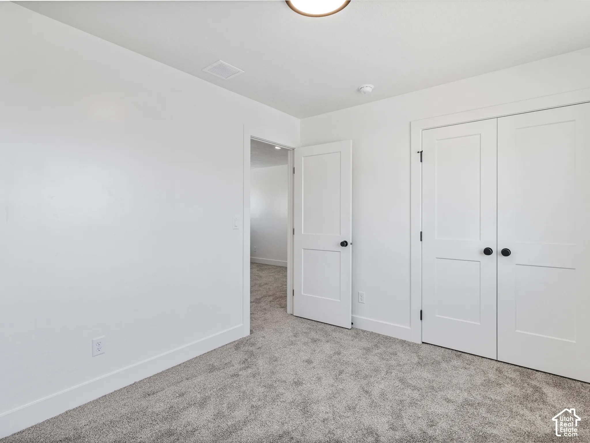 Plush gray carpeting, white painted walls, and white interior doors with black hardware
