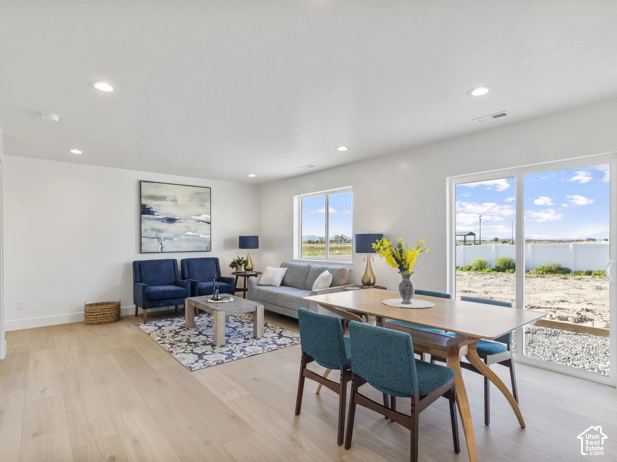 Recessed ceiling lighting, light wood-finish flooring, white walls, and a sliding glass door to the exterior