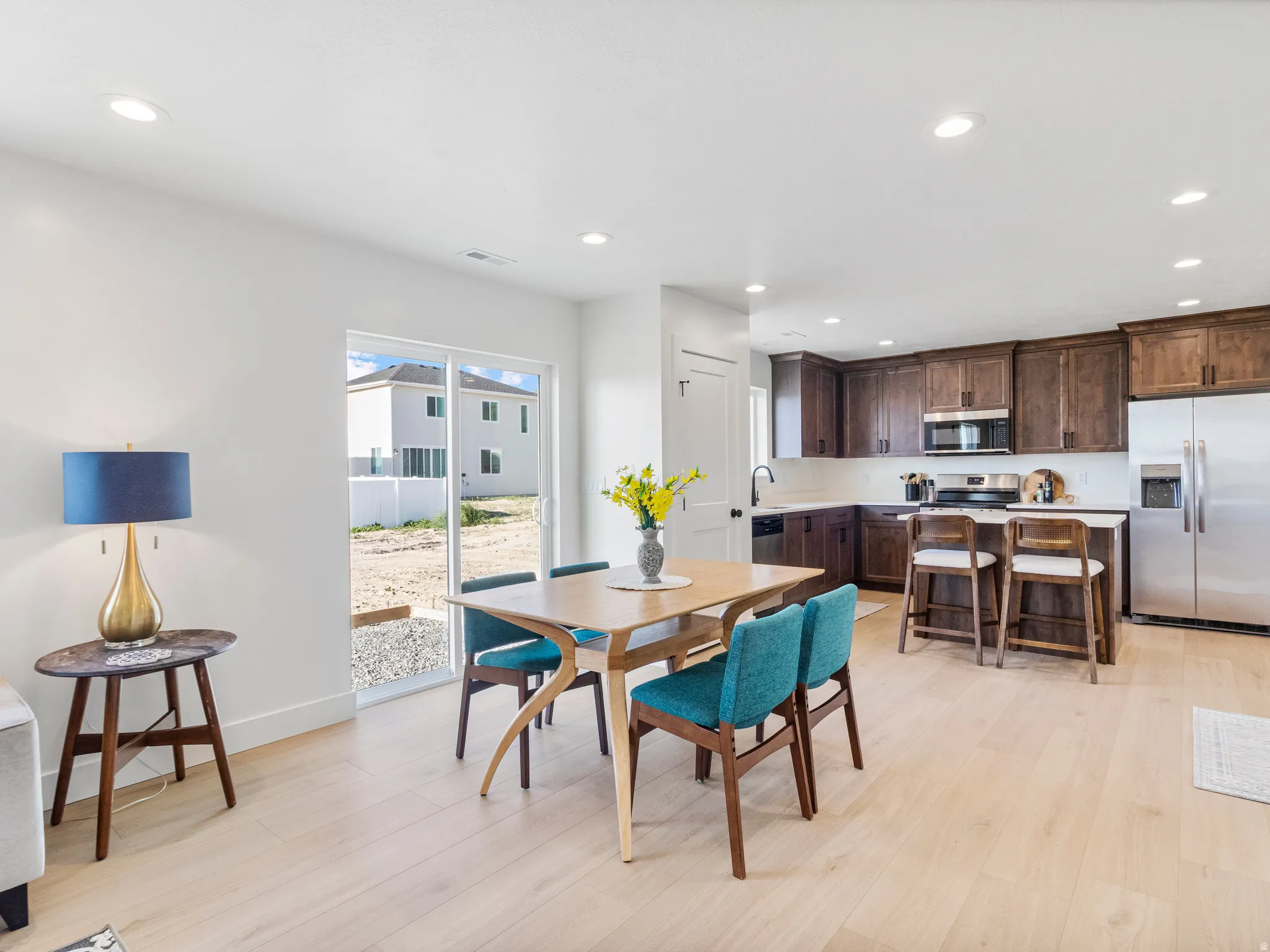 Open-concept living space with light wood-finish flooring, recessed lighting, and a sliding glass door