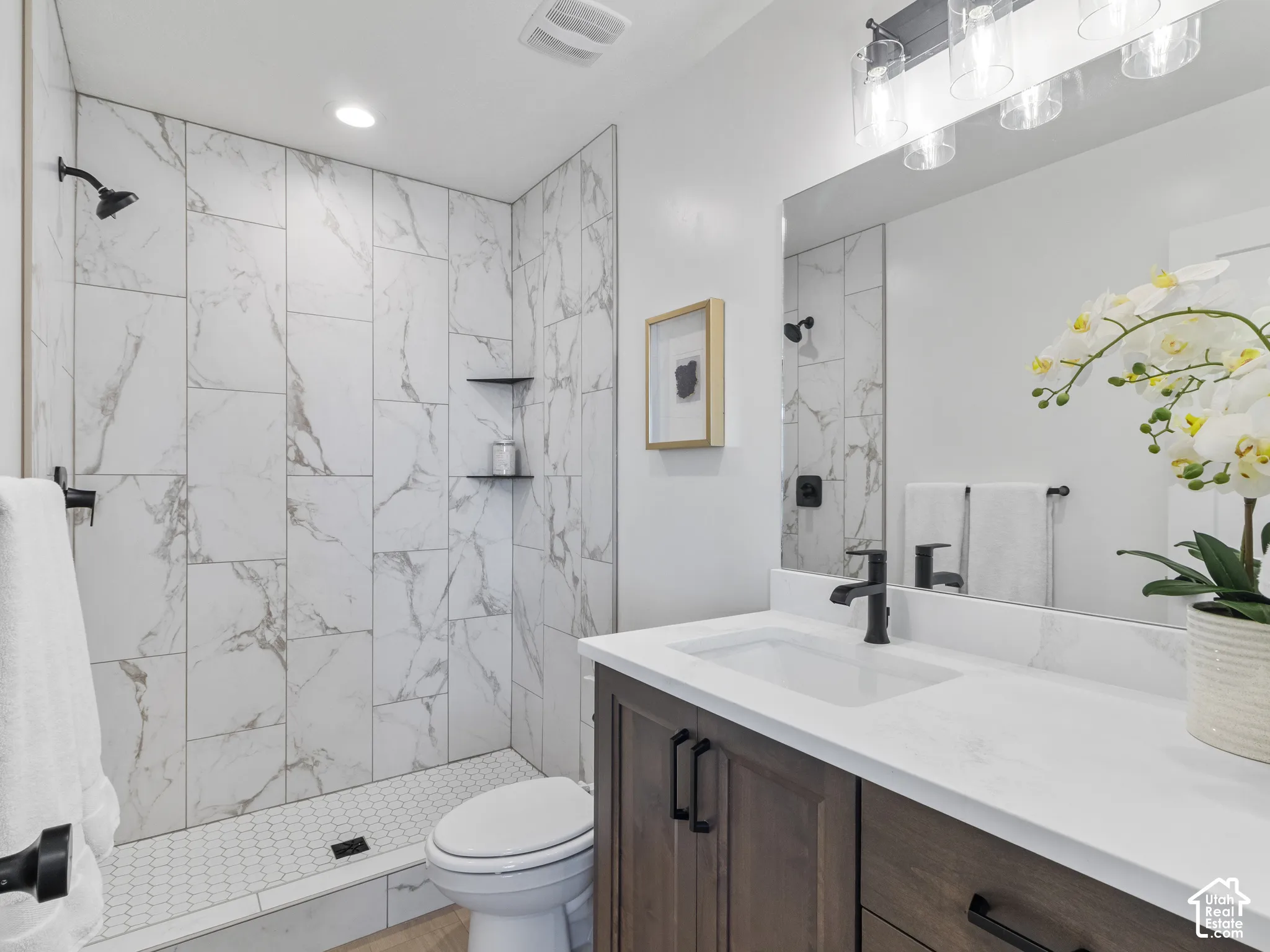 Walk-in shower with full-height marble-look tile surround and hex tile floor