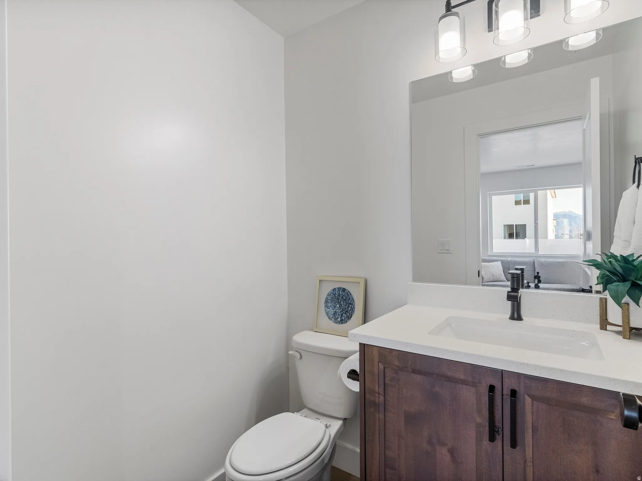 Bathroom featuring a wood-finish vanity with black hardware, white countertop, and an integrated rectangular sink