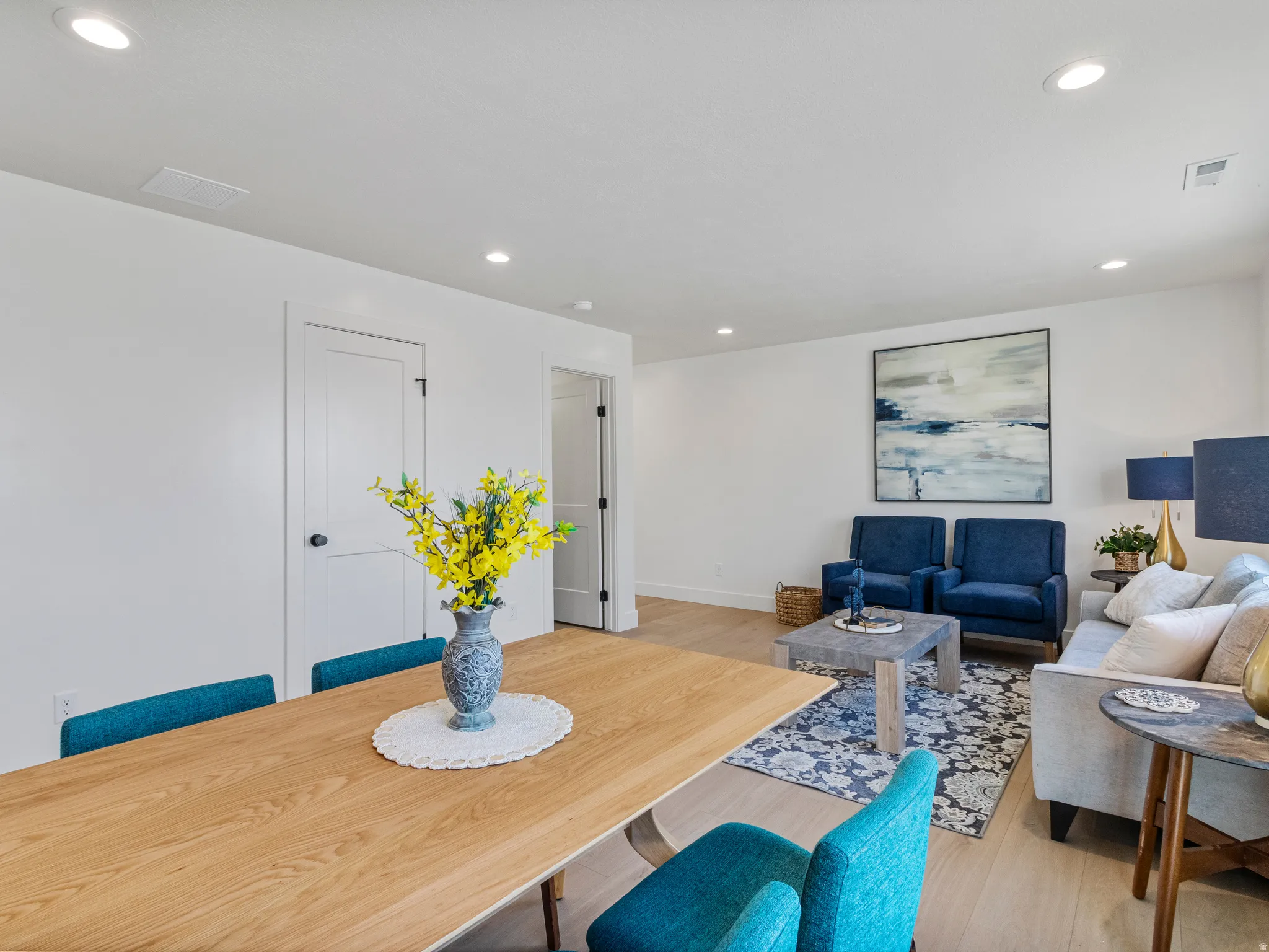 Recessed lighting illuminates the open-concept living space, featuring wood-finish flooring and white interior doors with black hardware