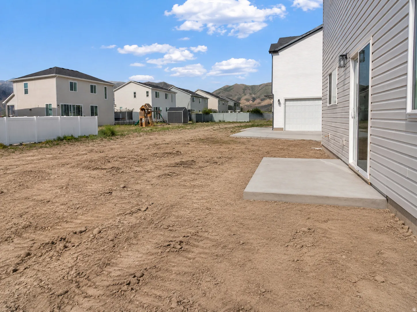Rear yard with a concrete patio pad and a sliding glass door. AI was used to update the photo with the completed concrete.