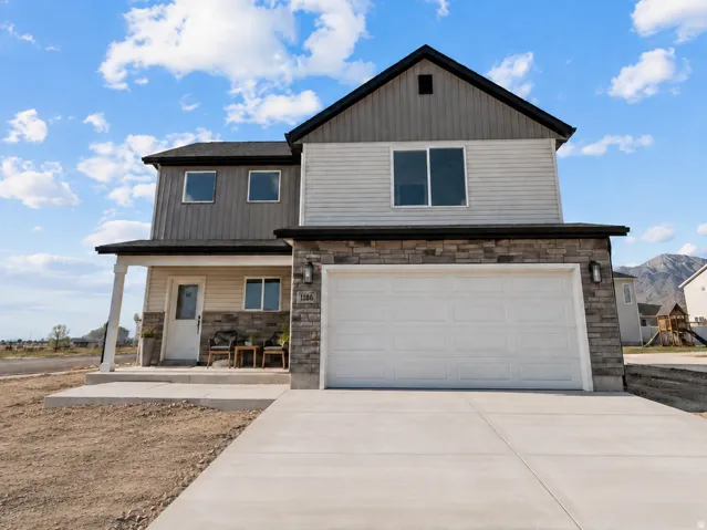 Modern exterior with mixed siding, stone veneer accents, an attached garage, and a covered porch. AI was used to update the photo with the completed concrete.