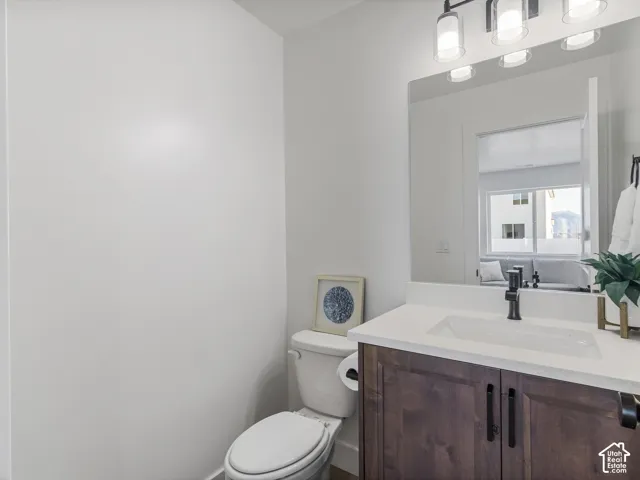 Bathroom featuring a wood-finish vanity with black hardware, white countertop, and an integrated rectangular sink