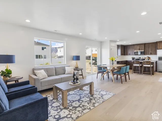 Open-concept living area with light wood-finish flooring, recessed lighting, and a large window