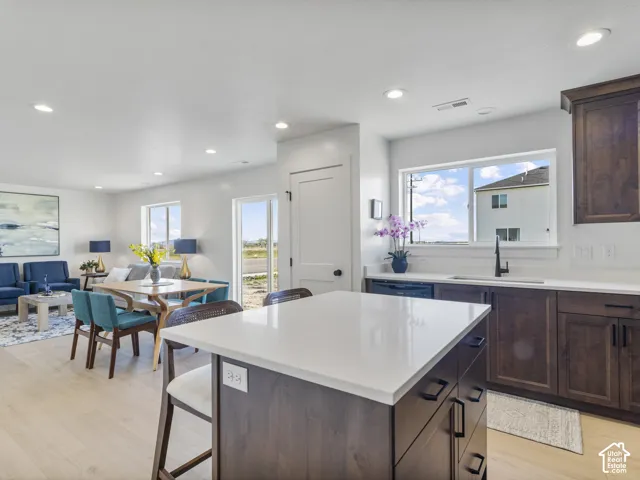 Kitchen island with white countertop, dark wood-finish cabinetry, and recessed lighting