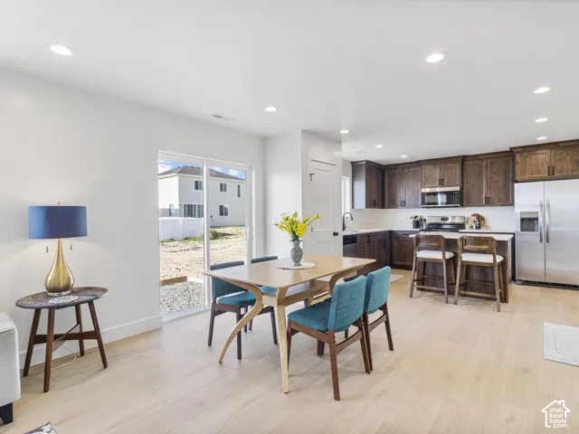 Open-concept living space with light wood-finish flooring, recessed lighting, and a sliding glass door