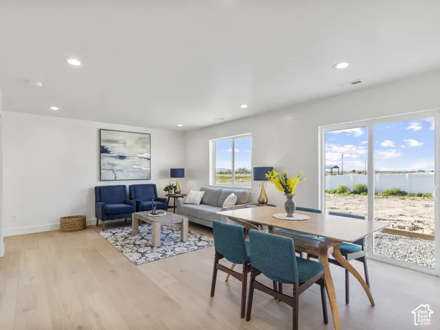 Recessed ceiling lighting, light wood-finish flooring, white walls, and a sliding glass door to the exterior
