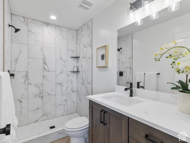 Walk-in shower with full-height marble-look tile surround and hex tile floor