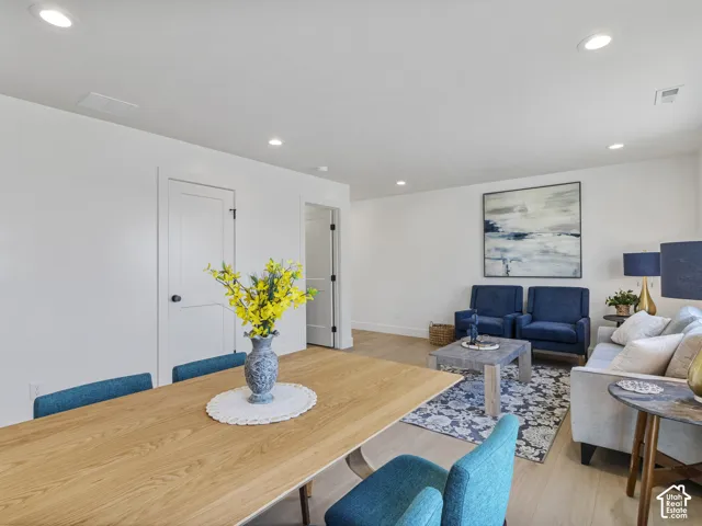 Recessed lighting illuminates the open-concept living space, featuring wood-finish flooring and white interior doors with black hardware