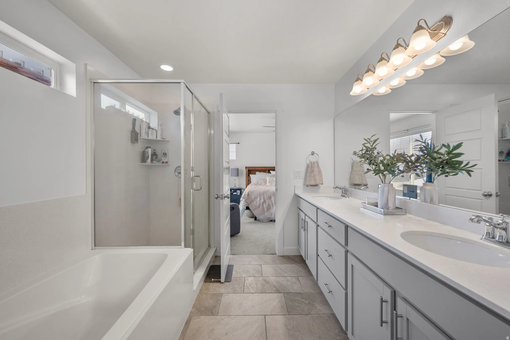 Dual vanity with under-mount sinks, a white countertop, and expansive mirror