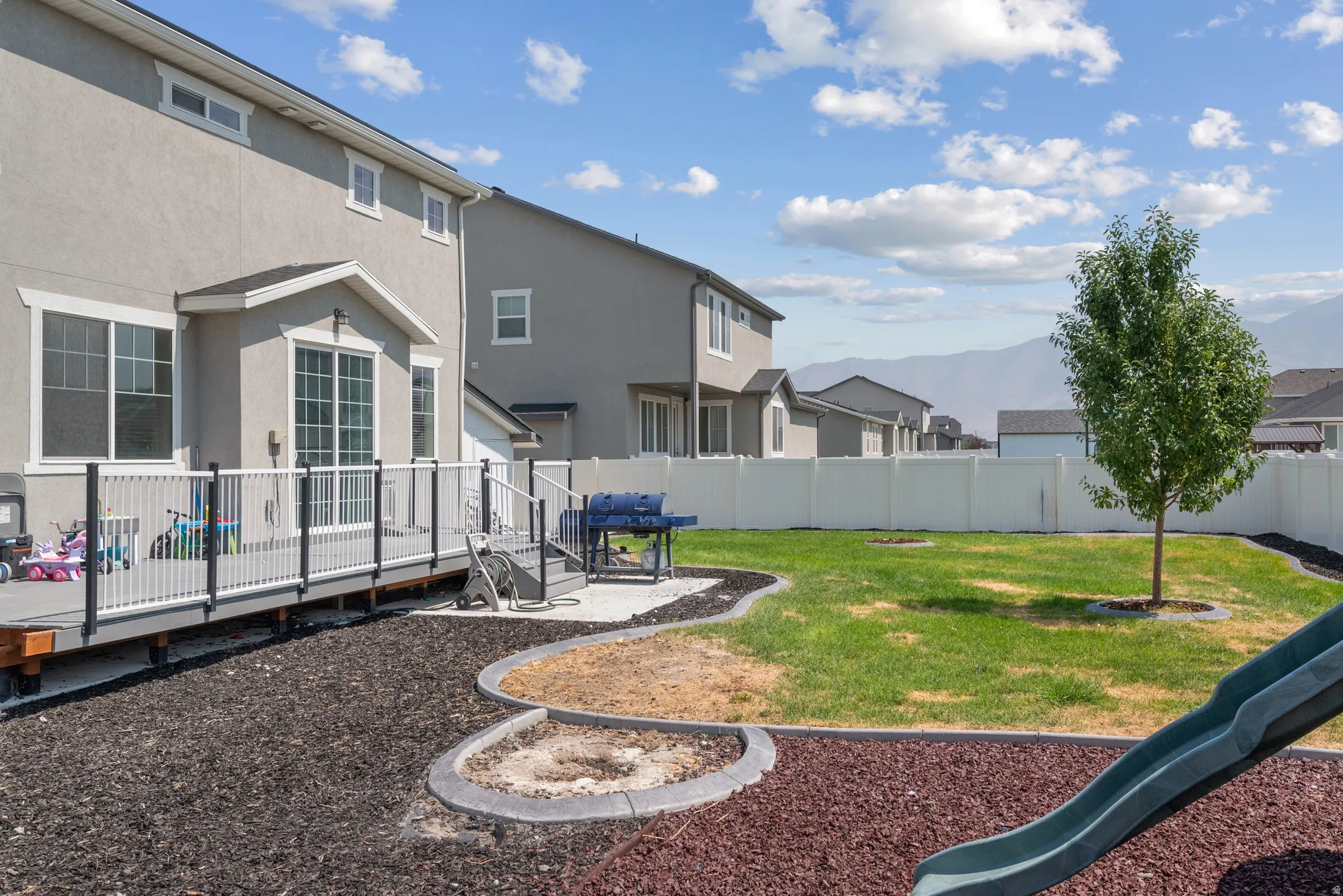 Spacious backyard featuring a full privacy fence, established lawn, and a multi-level deck with a railing system