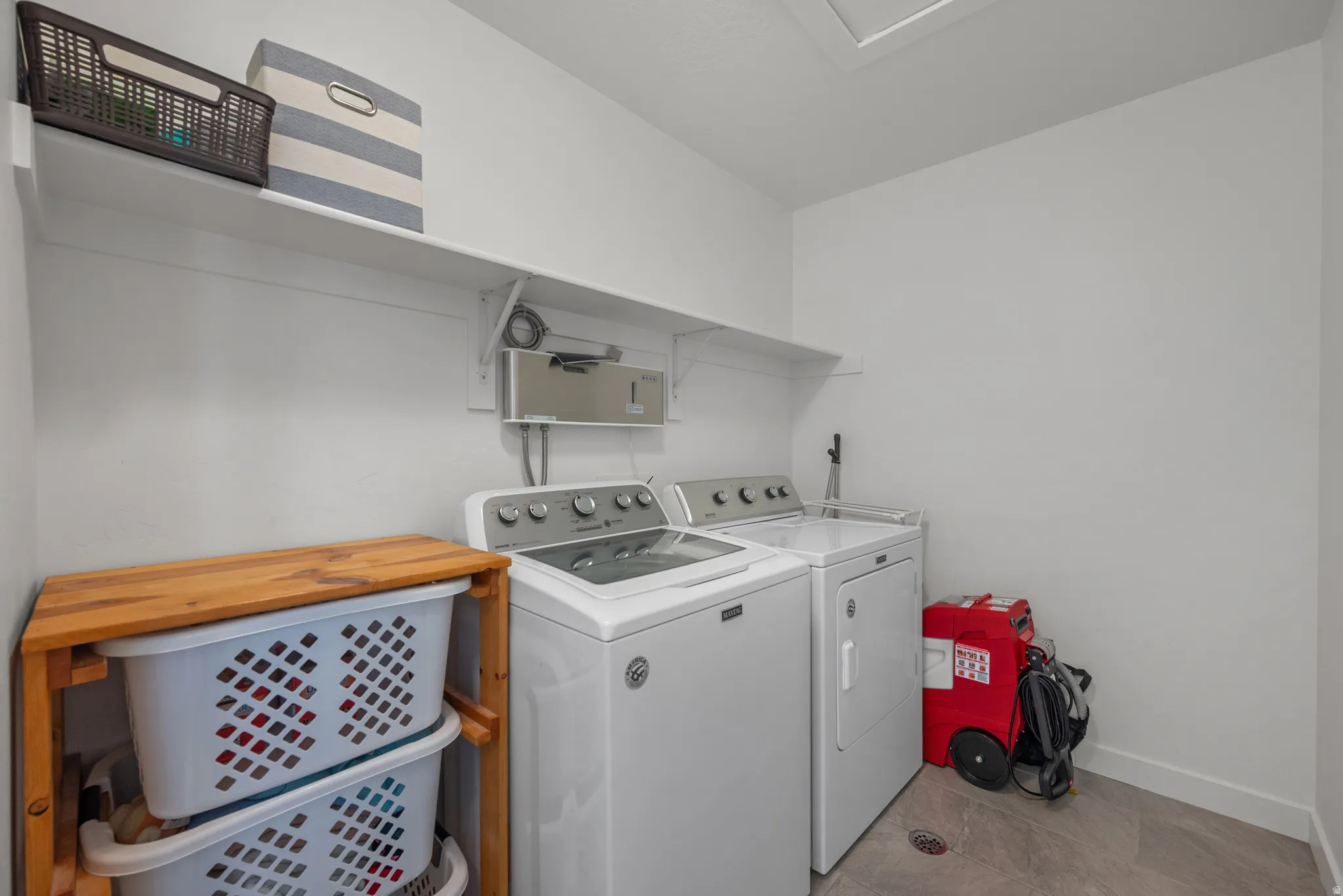 Laundry room featuring a full-size washer and dryer, wall-mounted shelving, and wood-finish flooring