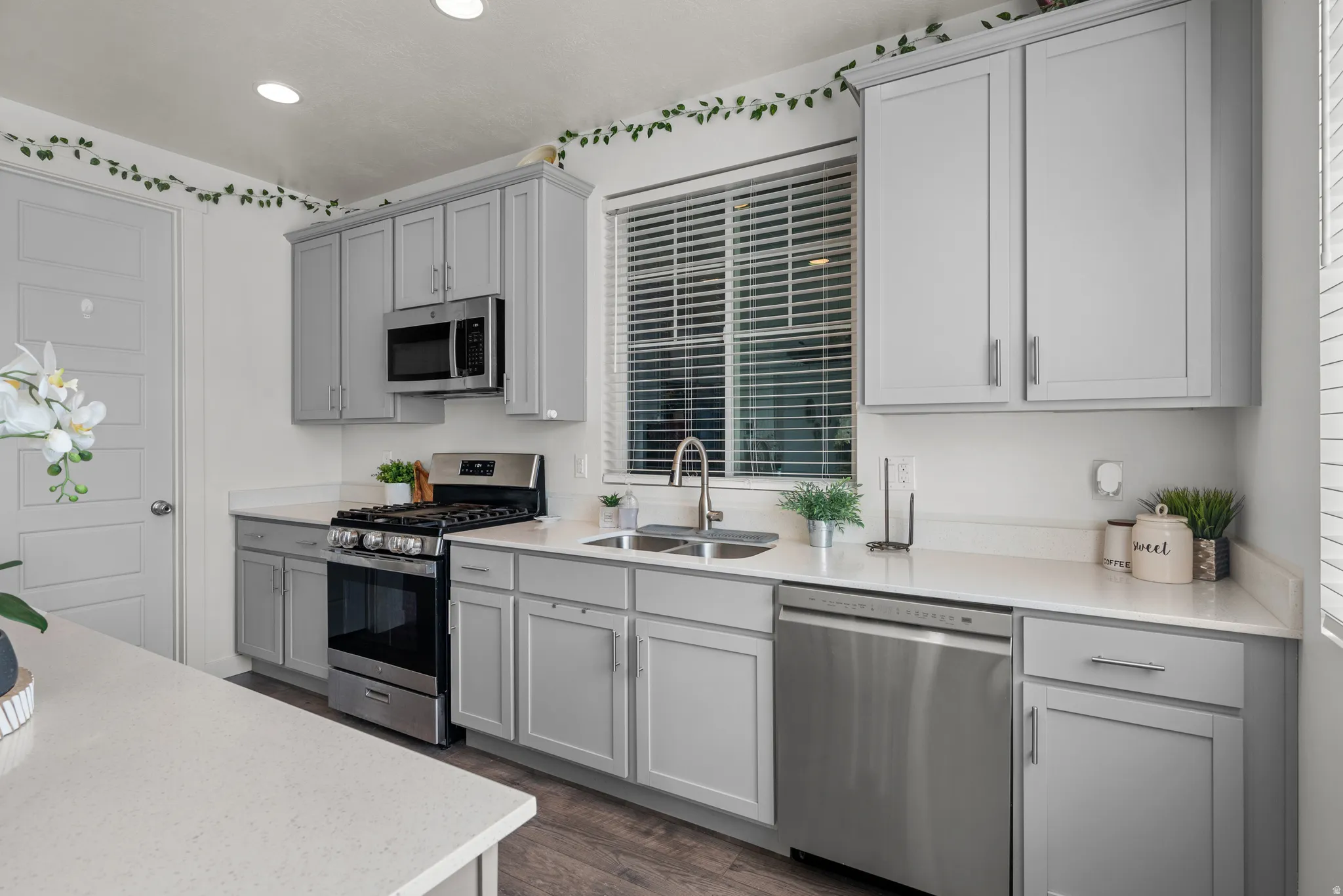 Contemporary kitchen with light gray cabinetry, stainless steel appliances, and white countertops