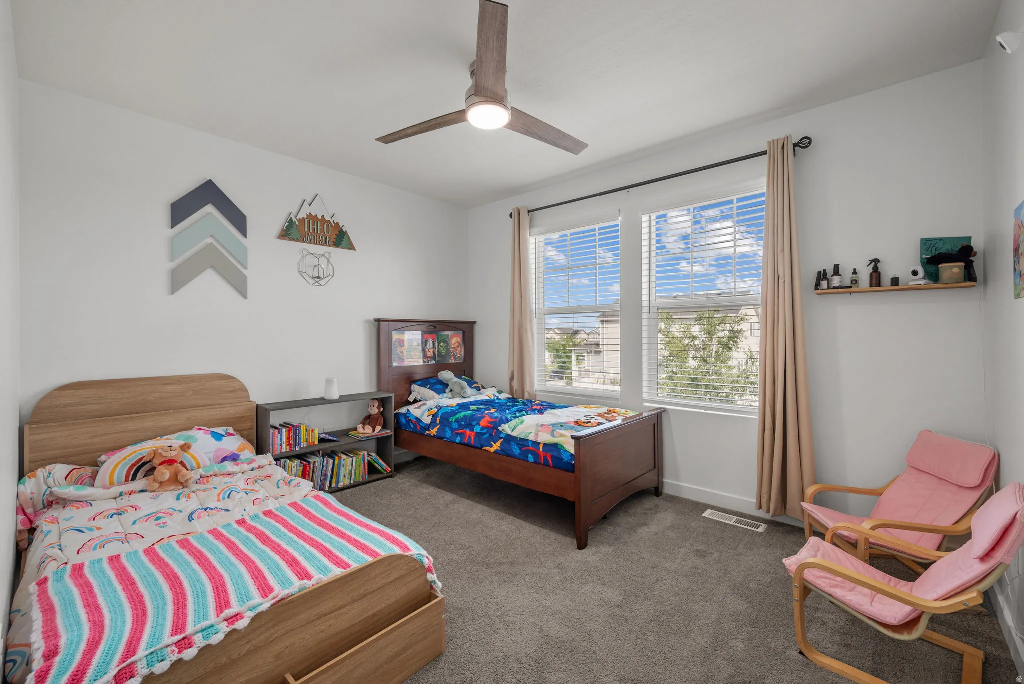 White painted walls, gray carpet flooring, two windows with blinds, and a ceiling fan with integrated lighting