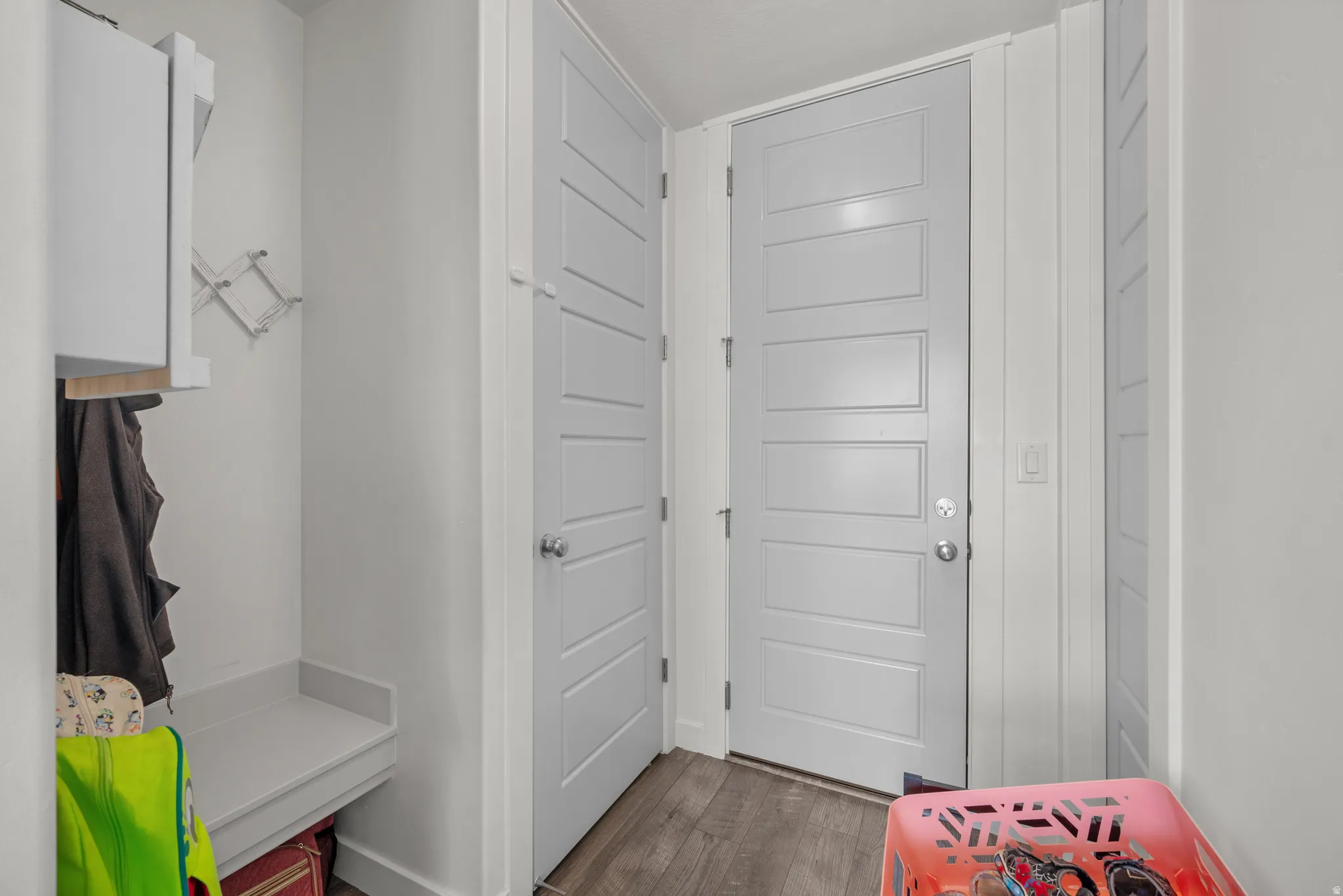 Muted gray doors with horizontal paneling, built-in bench seating, wood-finish flooring, and white cabinetry