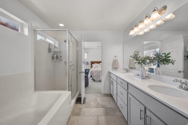 Dual vanity with under-mount sinks, a white countertop, and expansive mirror