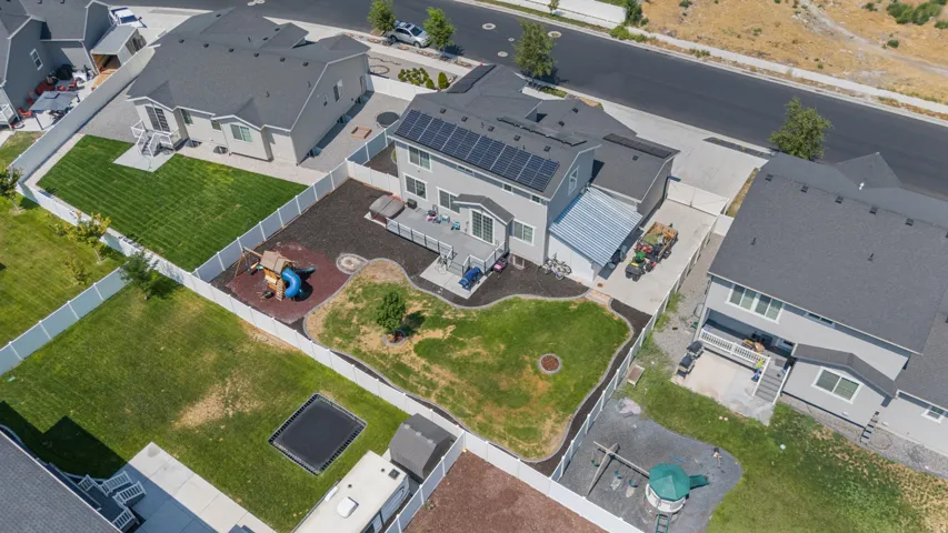 Two-story residence with a multi-level deck, fenced backyard, and solar panels on the roof