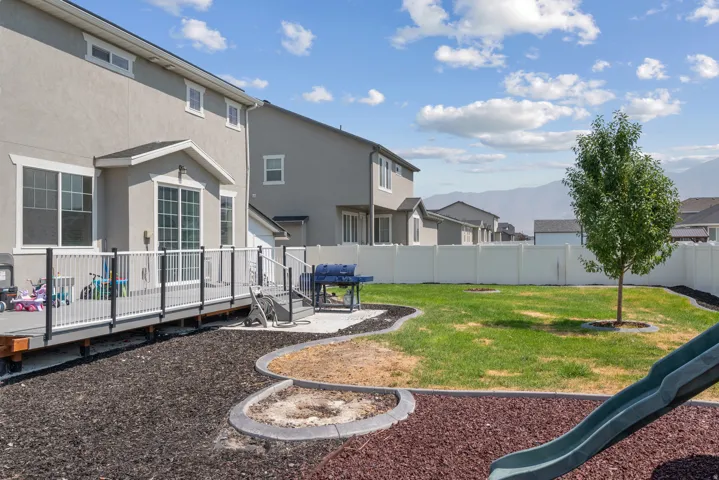 Spacious backyard featuring a full privacy fence, established lawn, and a multi-level deck with a railing system