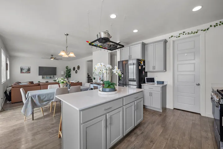 Kitchen island with a light-toned countertop, gray cabinetry, wood-finish flooring, recessed lighting, and a pot rack