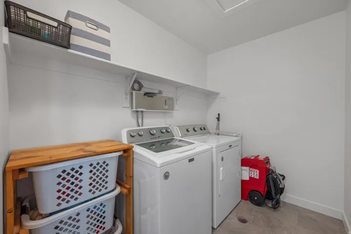 Laundry room featuring a full-size washer and dryer, wall-mounted shelving, and wood-finish flooring