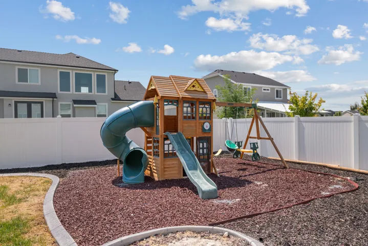 Fenced backyard with landscape edging, a wood chip play area, and an additional grass area