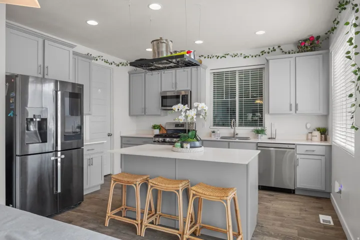 Kitchen featuring wood-finish flooring, recessed lighting, light gray cabinetry, stainless steel appliances, and a central island with a white countertop