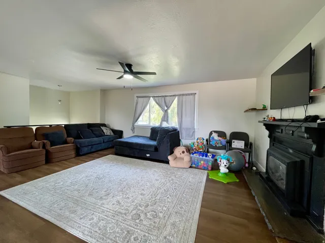 Hardwood-finish flooring, built-in fireplace, natural light from windows, overhead lighting, and an open concept layout