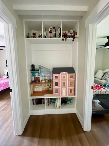 Built-in shelving unit with white finish, wood-finish flooring, and white trim