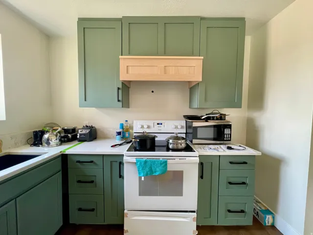 Kitchen featuring shaker-style cabinetry, white countertops, and a built-in range hood enclosure