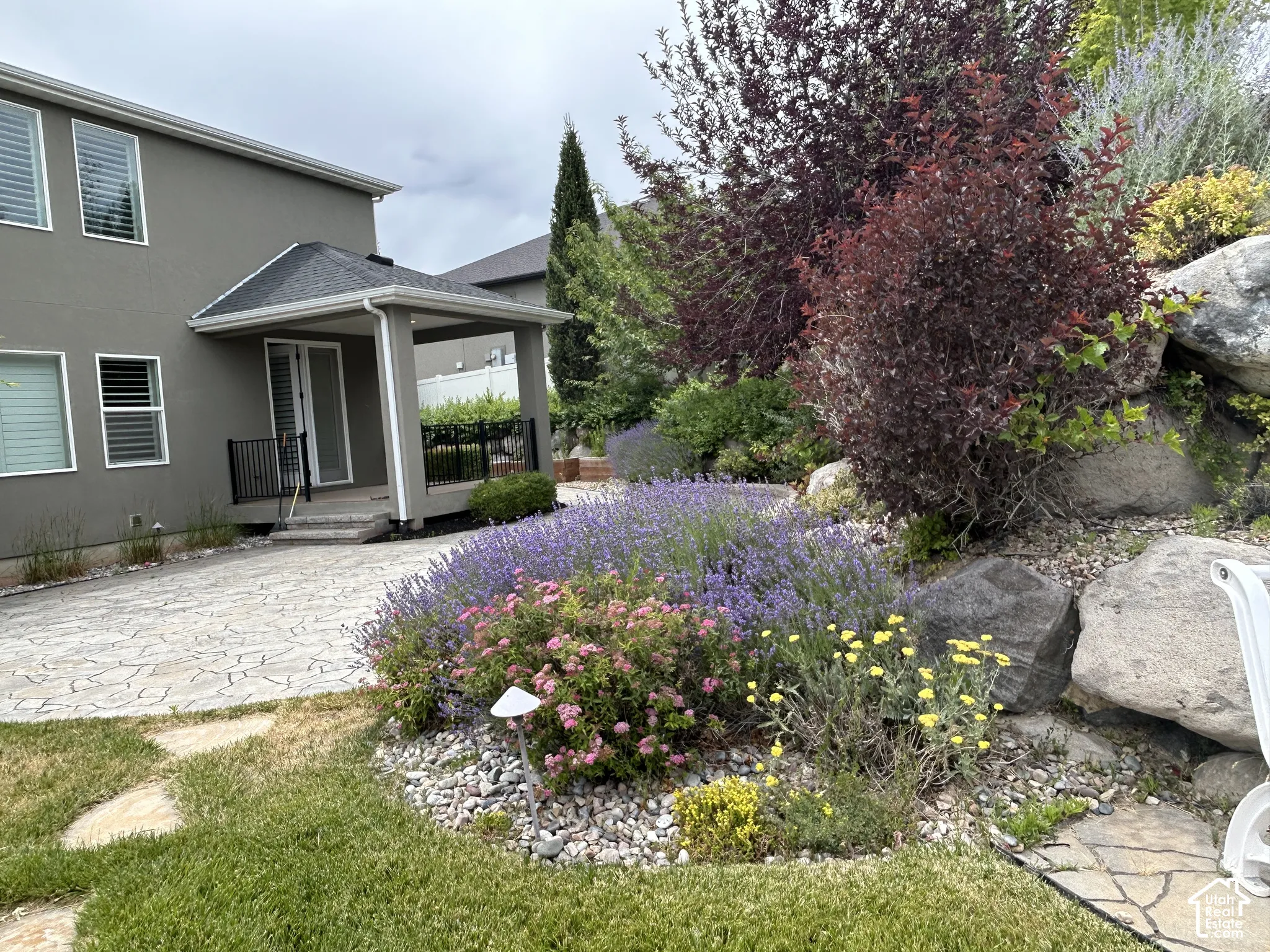 Patio with a covered porch, an expansive paved area, and a rock garden featuring diverse plantings