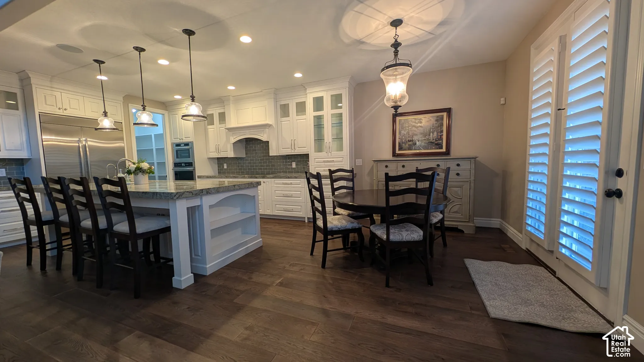 Gourmet kitchen with white cabinetry, stainless steel appliances, a large island with seating, and a tiled backsplash