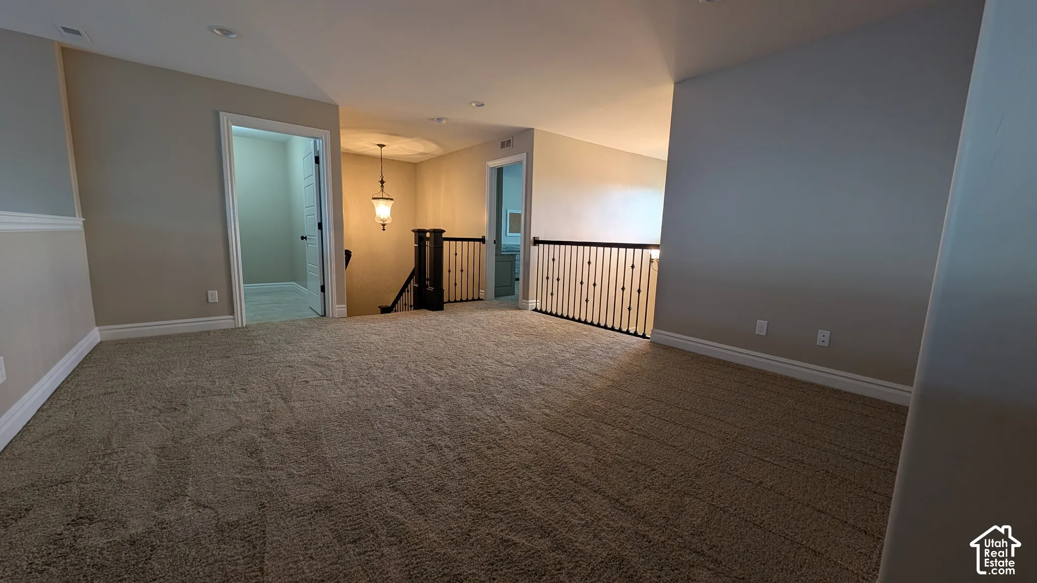 Large Carpeted loft area with recessed lighting, painted walls, white trim, and a dark wood and metal spindle railing. Great for playroom, media or game room