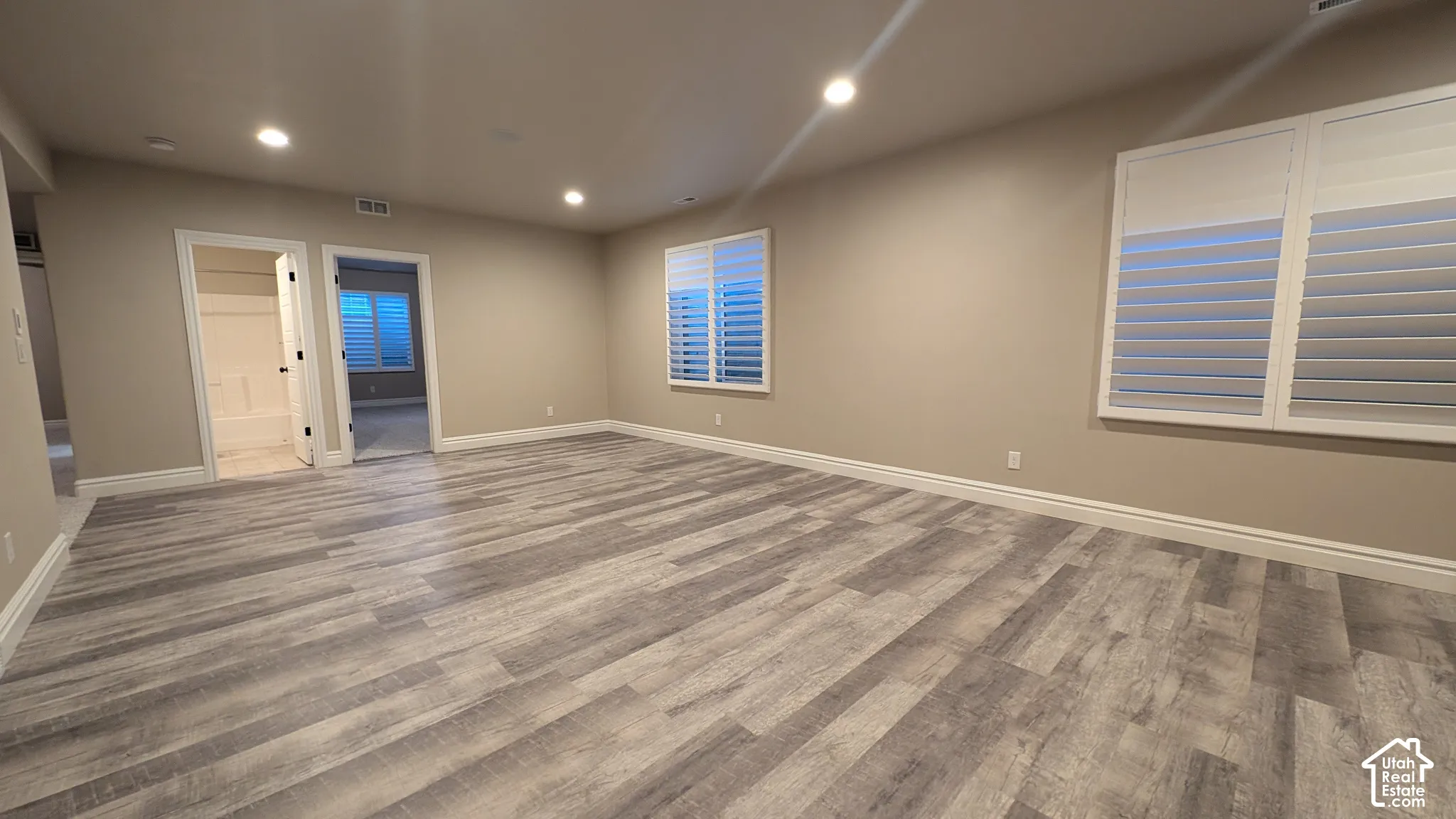 Other view of large family room with Expansive room featuring wood-finish flooring, recessed lighting, and windows with white plantation shutters