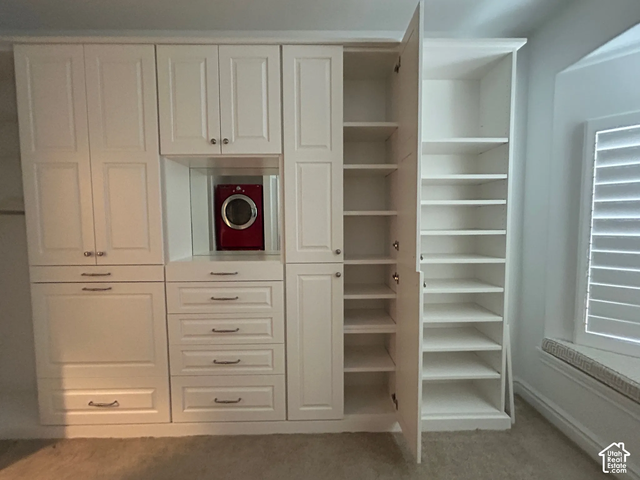 Built-in white cabinetry with various storage options, including drawers and shelving