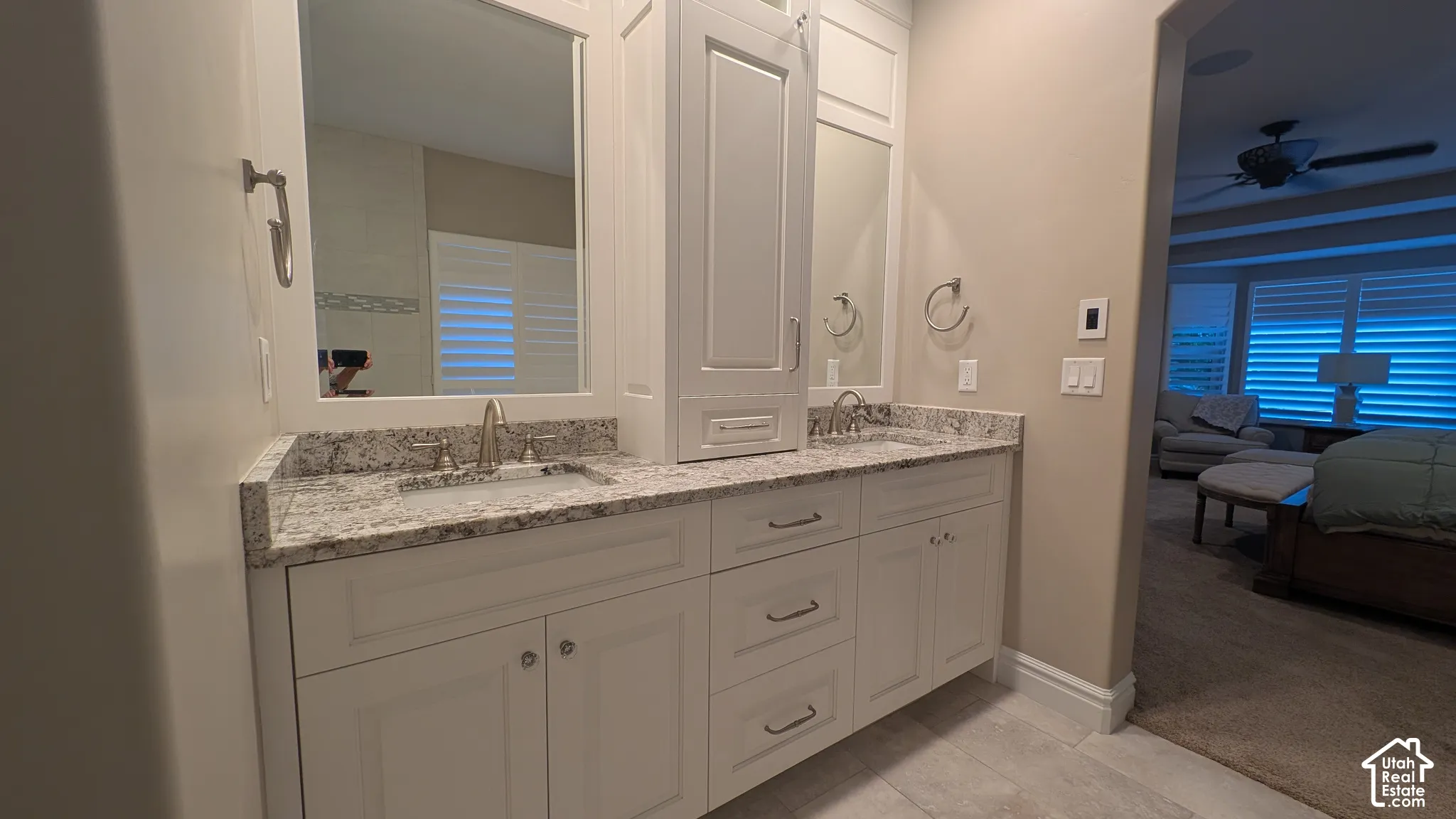 Dual basin vanity with stone countertop, white shaker cabinetry, and brushed nickel fixtures
