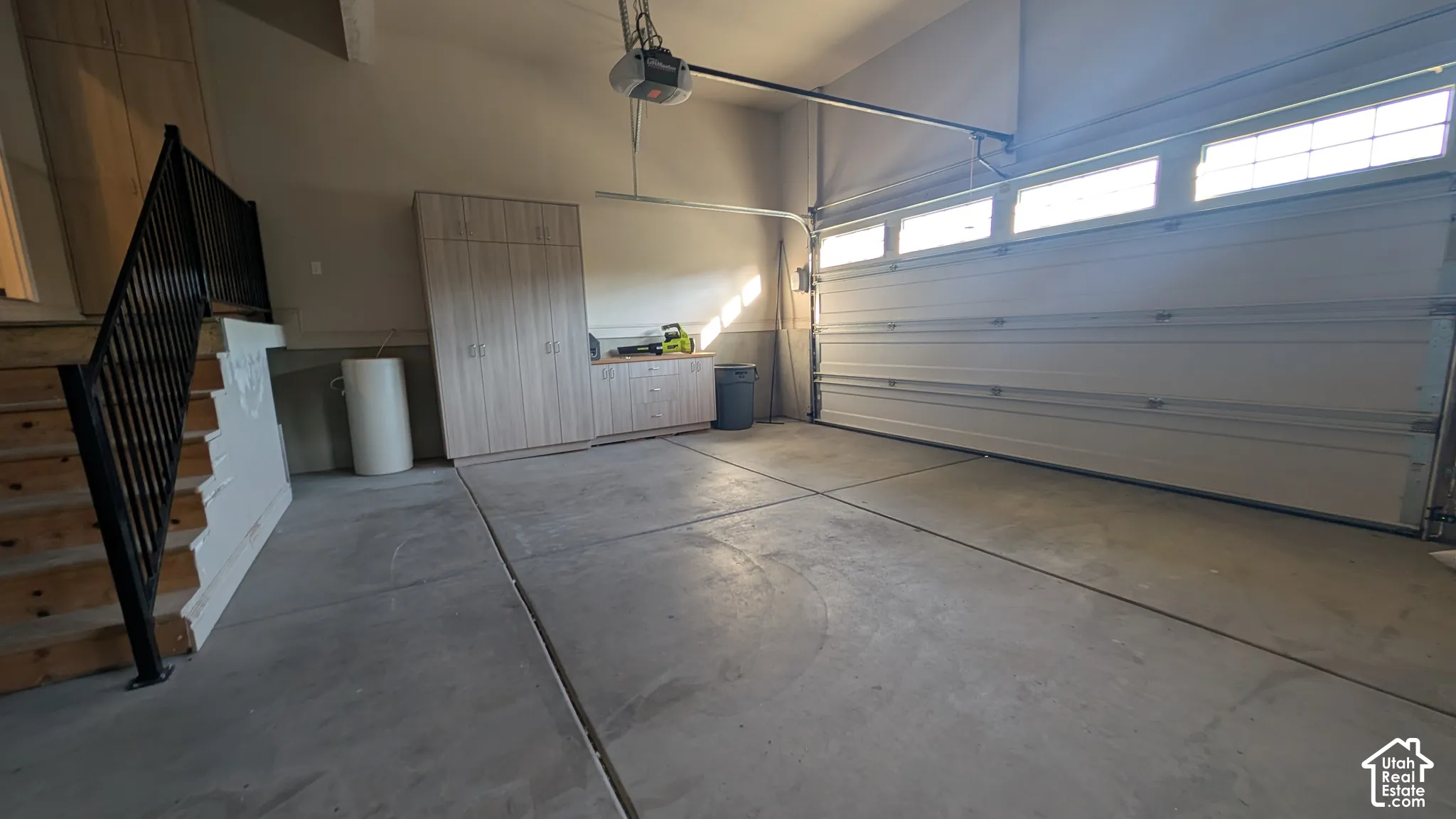 Attached garage with concrete flooring, built-in cabinetry, and a garage door featuring upper windows