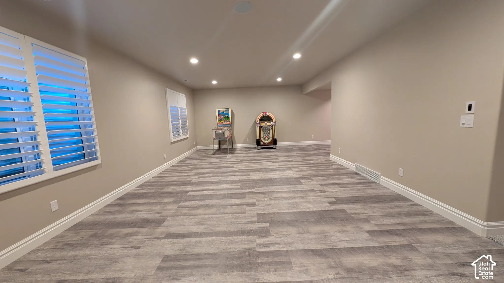 Huge family, recreation room with new carpet and paint, Recessed lighting illuminating wood-finish flooring, neutral-toned walls, and white plantation shutters