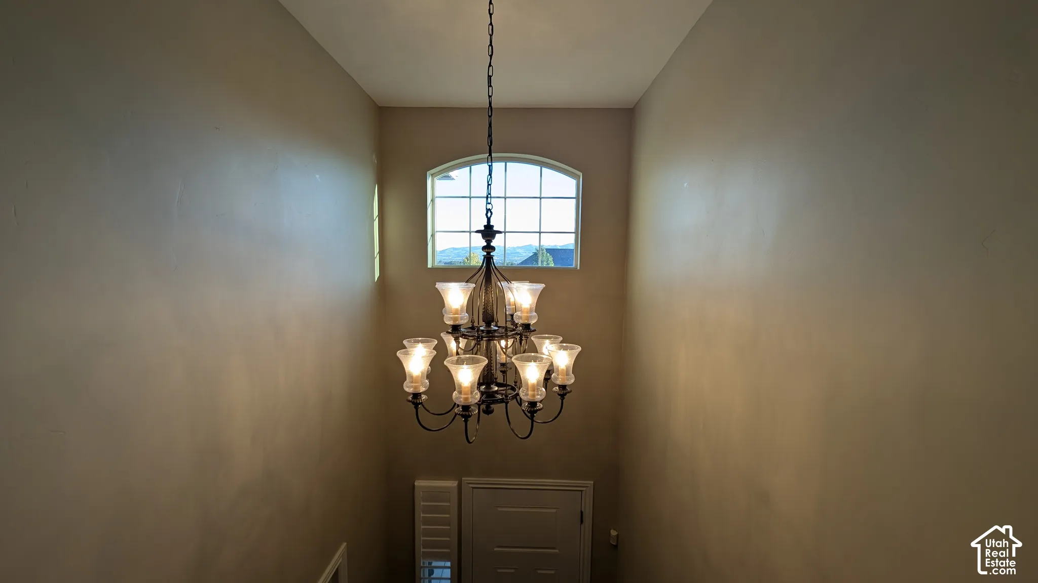 Vaulted ceiling with an arched window, featuring a multi-light chandelier